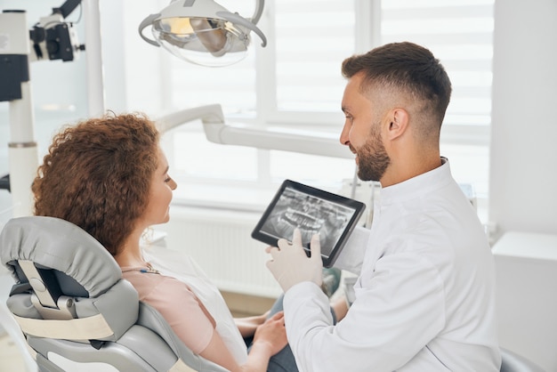 Foto dentista masculina trabalhando na clínica odontológica moderna