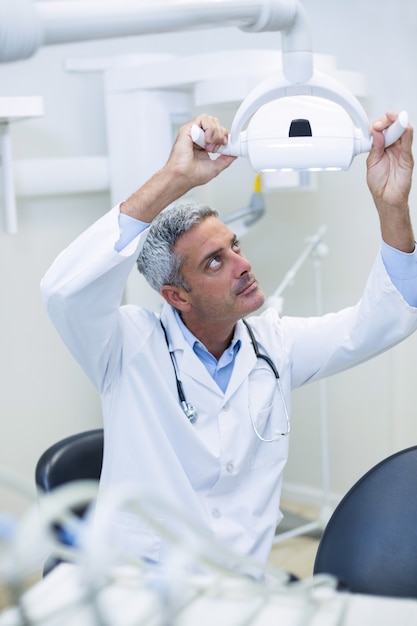 Dentista masculino, ajustando a luz