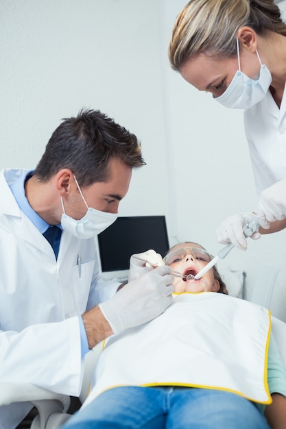 Dentista masculino com assistente de dentes de meninas examinadoras