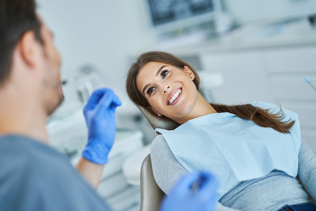 Dentista masculino e mulher em consultório dentário