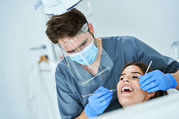 Dentista masculino e mulher em consultório dentário