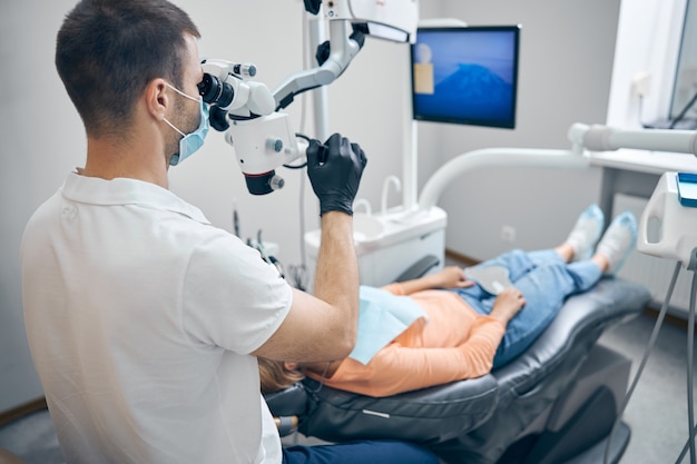 Dentista masculino con equipo moderno durante la cita con la mujer