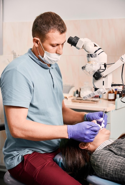 Dentista masculino examinando los dientes del paciente en el consultorio dental