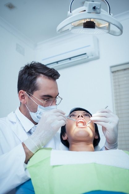 Dentista masculino examinando os dentes da mulher