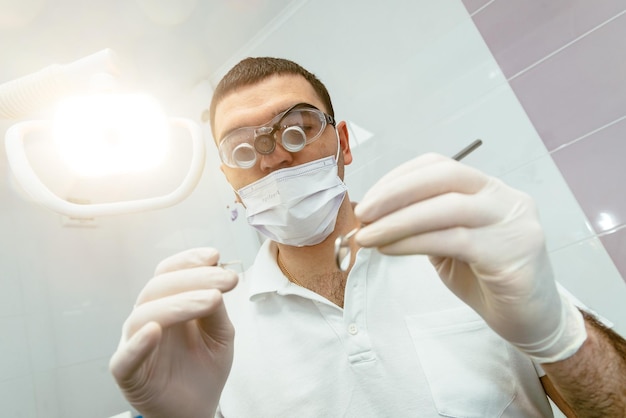 Dentista masculino con herramientas que van a hacer el examen de los dientes de los pacientes 39 en la oficina del dentista