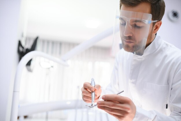 Foto dentista masculino jovem na clínica