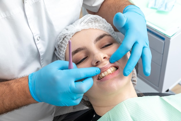 El dentista masculino mira una mandíbula de una paciente femenina chequeando la mordida