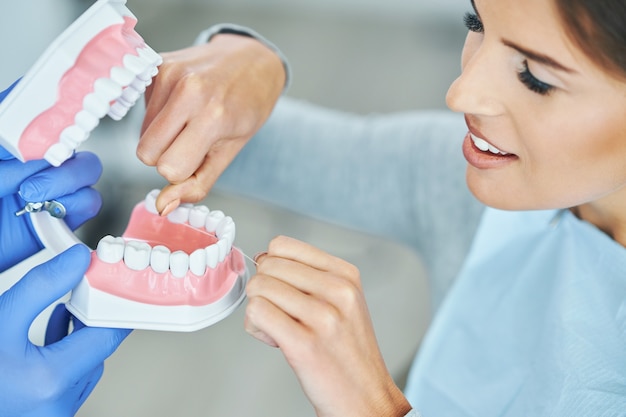 Dentista masculino y mostrando la mandíbula a la mujer en la clínica dental