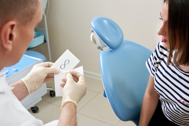 Dentista masculino mostrando a su paciente un implante dental en la clínica moderna