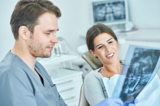 Foto dentista masculino y mujer discutiendo los resultados de rayos x en el consultorio del dentista