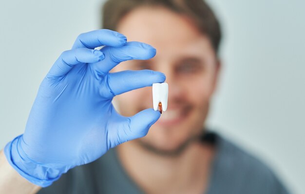 Dentista masculino que muestra la mandíbula y los dientes a la cámara en el consultorio del dentista