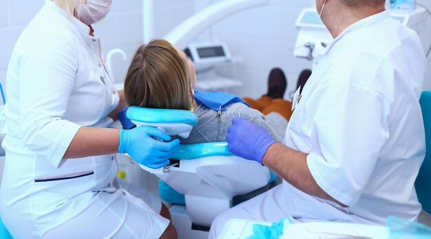 Dentista masculino sênior em consultório odontológico conversando com paciente do sexo feminino e se preparando para tratamento