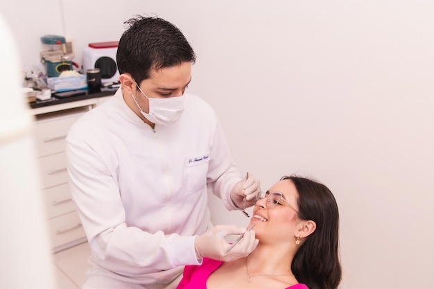 El dentista masculino trabajando en sus pacientes sonríe en el consultorio dental.