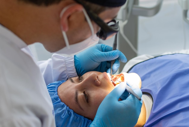 Dentista masculino en uniforme durante una intervención dental en una mujer Concepto de clínica dental