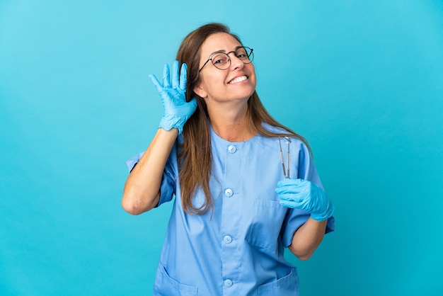 Dentista de mediana edad mujer brasileña sosteniendo herramientas sobre aislado