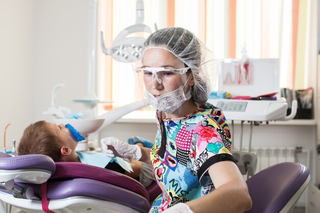 El dentista médico de niños pequeños trata los dientes con diferentes dispositivos