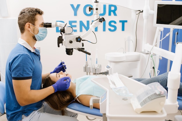 Un dentista mirando al microscopio los dientes de los pacientes