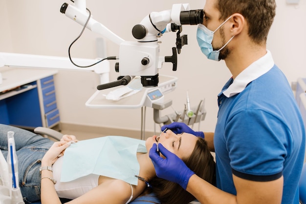 Un dentista mirando al microscopio los dientes de los pacientes