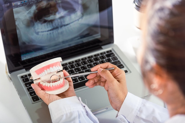 Dentista modelo de diente sano e instrumento de herramienta de espejo explorador en dentista explicando al paciente