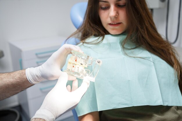 Dentista mostrando a técnica de limpeza dos dentes ao cliente.