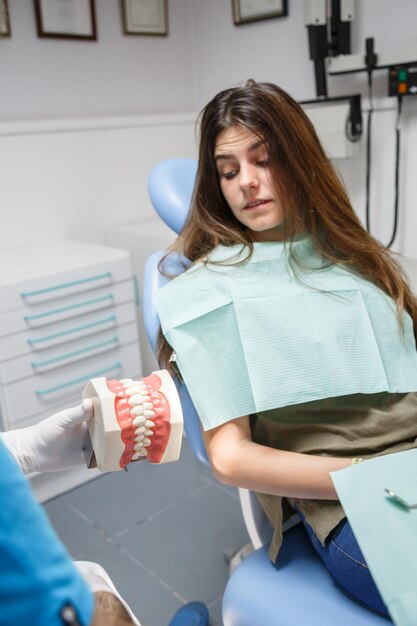 Dentista mostrando a técnica de limpeza dos dentes ao cliente.