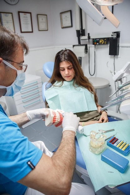 Dentista mostrando a técnica de limpeza dos dentes ao cliente.