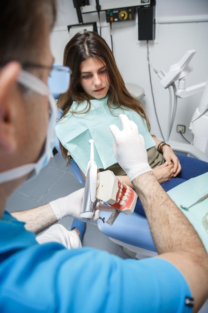 Dentista mostrando a técnica de limpeza dos dentes ao cliente.