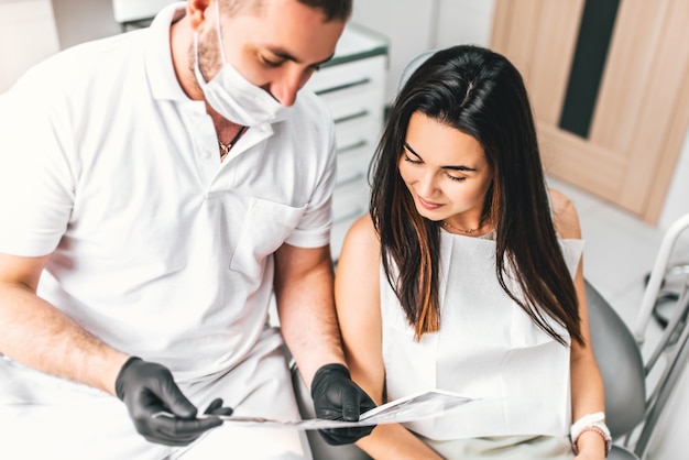 Dentista mostrando por el feliz resultado paciente del tratamiento.