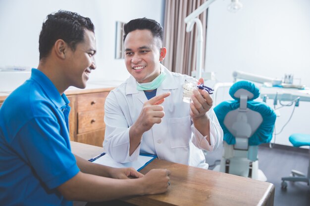 Dentista mostrando modelo de mandíbula dental