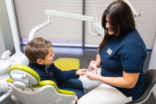 Dentista mostrando modelo de mandíbula para menino