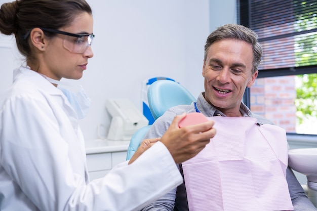 Dentista mostrando molde dental para homem