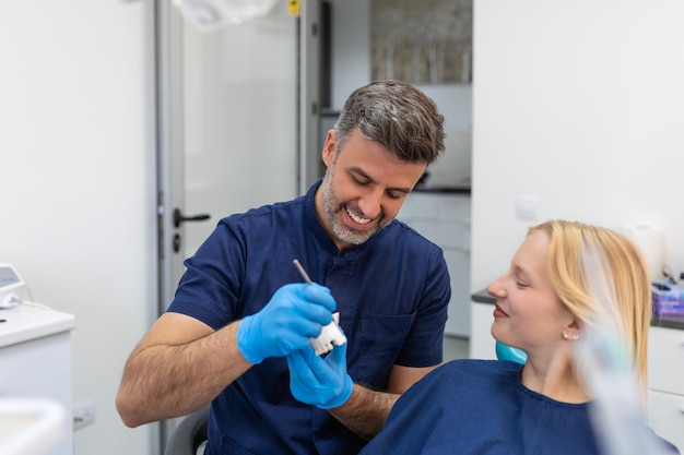 Dentista mostrando molde de yeso dental al paciente Médico dentista mostrando modelo de mandíbula en clínica dental concepto de cuidado dental Concepto de cuidado dental