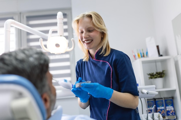 Dentista mostrando molde de yeso dental al paciente Médico dentista mostrando modelo de mandíbula en clínica dental concepto de cuidado dental Concepto de cuidado dental