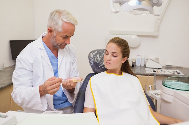 Dentista mostrando o modelo paciente de dentes