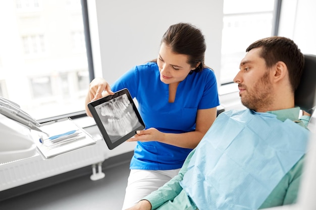 Foto dentista mostrando una radiografía dental panorámica al paciente