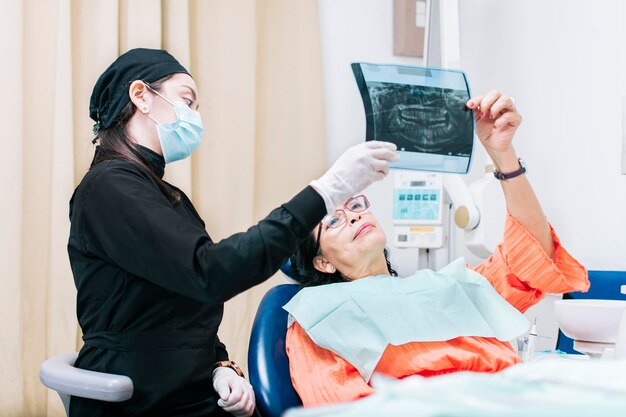 Dentista mostrando radiografía a paciente paciente mirando radiografía con dentista paciente dental sosteniendo su radiografía un dentista con examen de rayos x