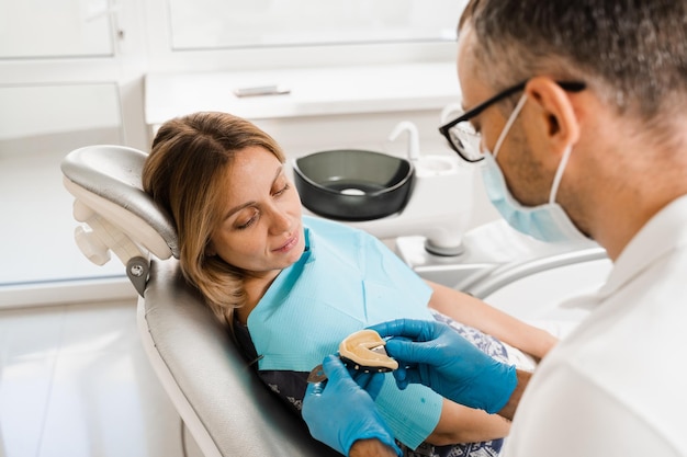 Dentista mostrando yeso de dientes de mujer paciente antes de la implantación dental Procedimiento de creación de prótesis dentales coronas y alineadores