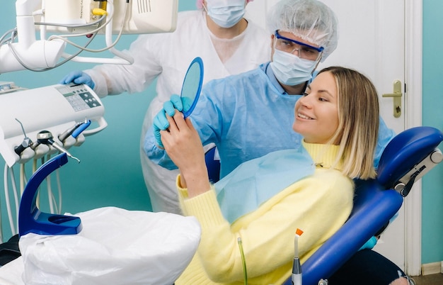 El dentista muestra al cliente los resultados de su trabajo en el espejo.