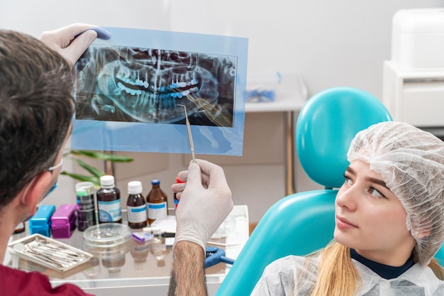 el dentista le muestra al paciente una imagen de la mandíbula e indica un problema