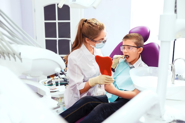 El dentista muestra una dentadura postiza al niño pequeño Niño con una sonrisa muy feliz después de que el médico de la clínica.