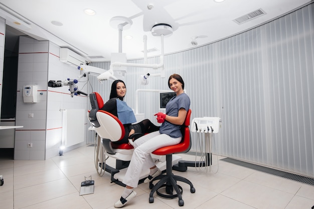 El dentista muestra una imagen de los dientes del paciente y le indica el tratamiento necesario. Odontología, salud.