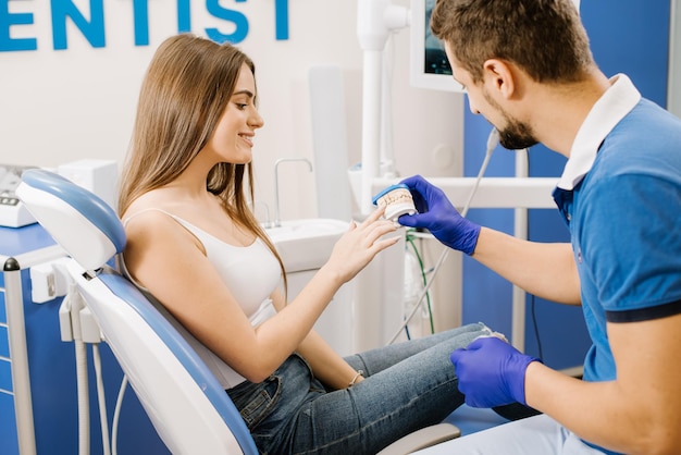 Un dentista muestra a la paciente un modelo cerámico de dientes y le explica sobre el trabajo