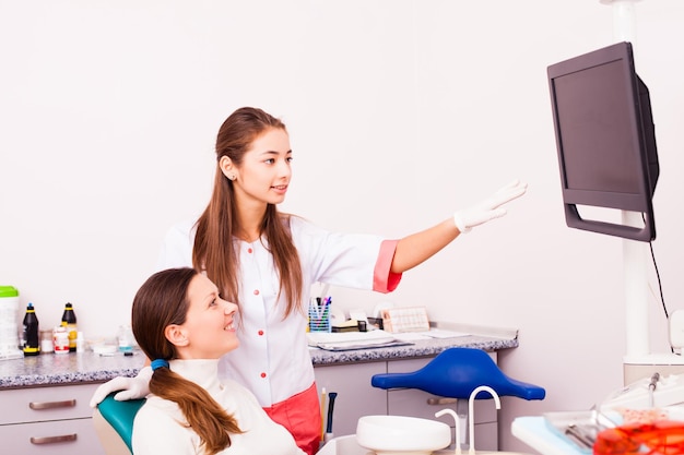 El dentista muestra a la paciente una radiografía en el monitor