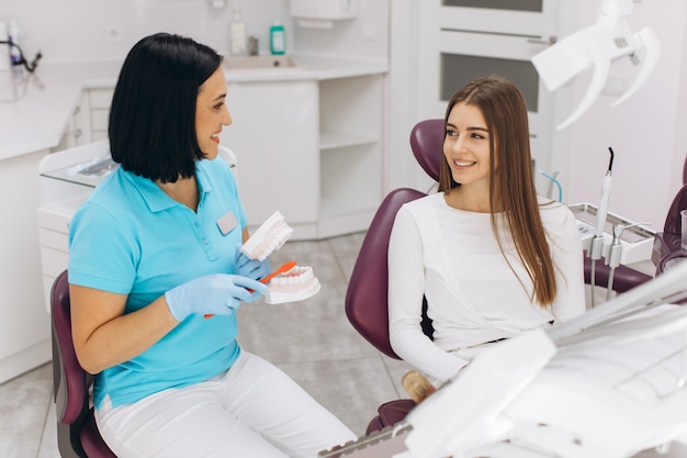 Una dentista le muestra a su paciente cómo cepillarse los dientes correctamente