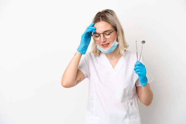 Dentista mujer caucásica sosteniendo herramientas aisladas sobre fondo blanco riendo