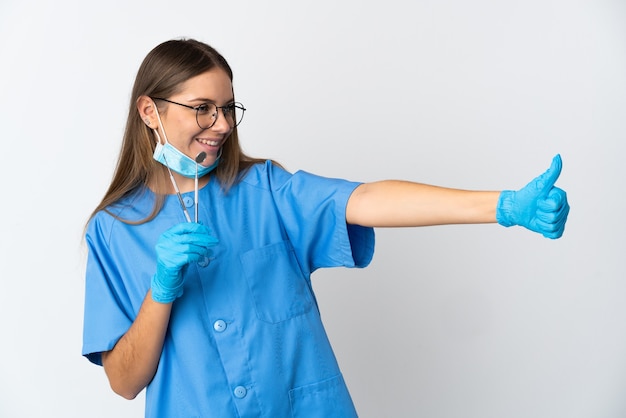 Foto dentista mujer lituana sosteniendo herramientas sobre pared aislada dando un pulgar hacia arriba gesto