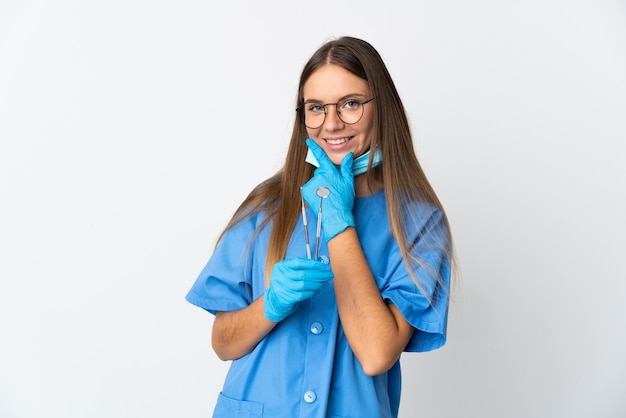 Dentista mujer lituana sosteniendo herramientas sobre pared aislada feliz y sonriente