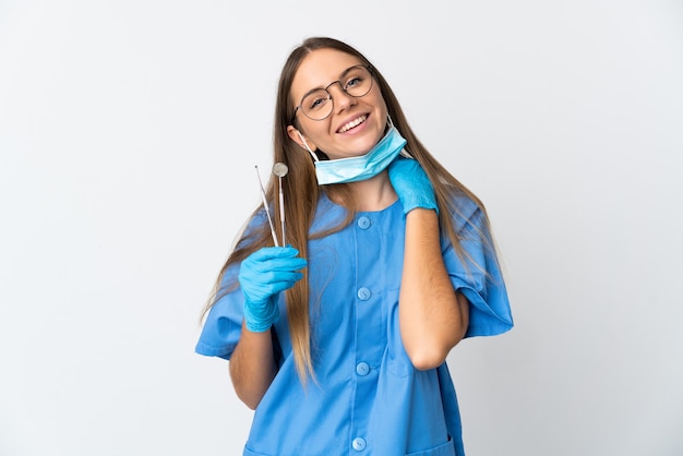 Dentista mujer lituana sosteniendo herramientas sobre pared aislada riendo