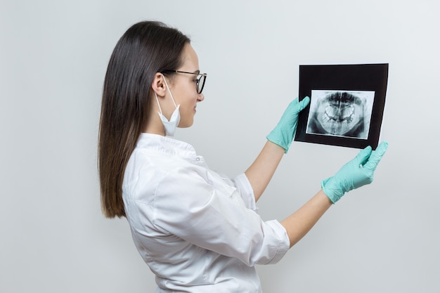 Dentista de niña con una bata blanca tiene una instantánea de los dientes del paciente.