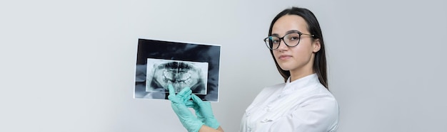Foto dentista de niña con una bata blanca tiene una instantánea de los dientes del paciente.